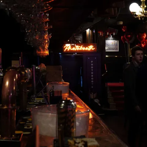 People are seated at small round tables in a dimly lit venue, watching a presentation on stage with a screen displaying "TWISTED50 VOL IV AWARDS.