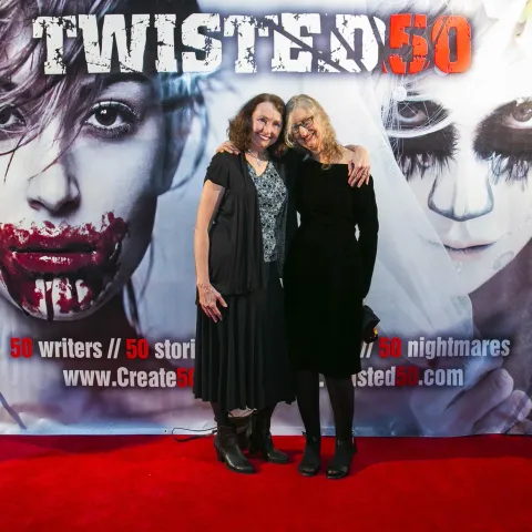 A woman and a girl standing next to a poster for twisted 50.