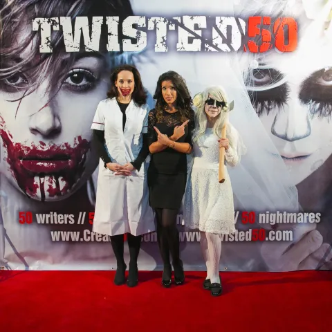 A man and woman posing in front of a poster for twisted 50.