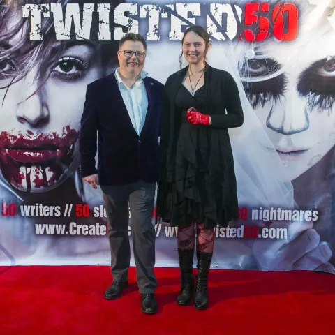 A man and woman posing on the red carpet for twisted 50.