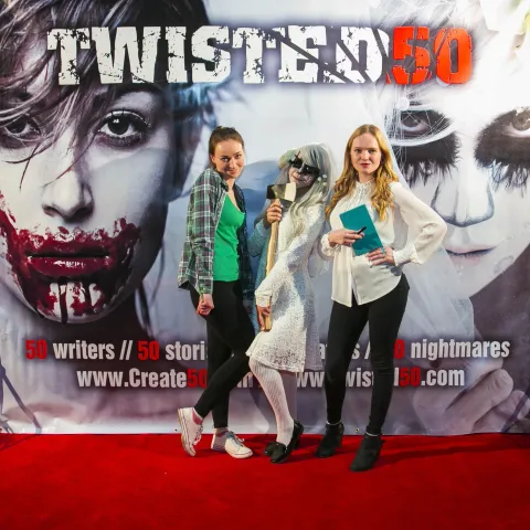 A man and woman posing in front of a poster for twisted 50.