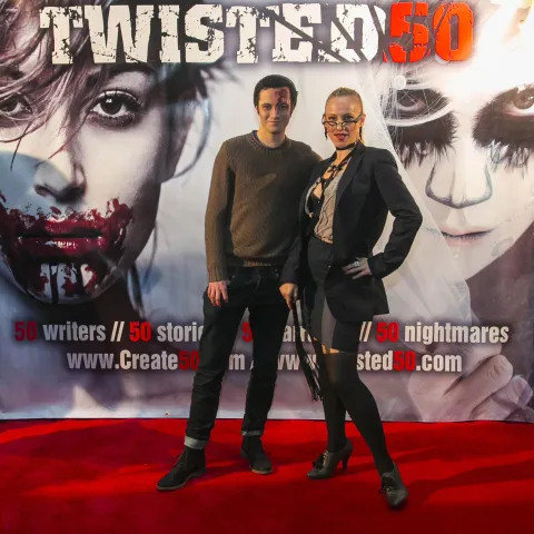 A woman and a girl standing next to a poster for twisted 50.