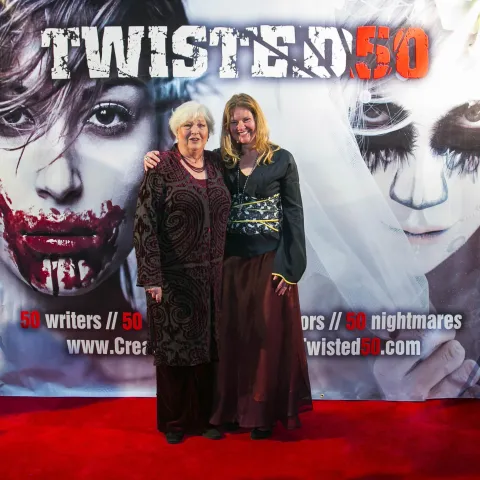 Two men standing in front of a poster for twisted 50.