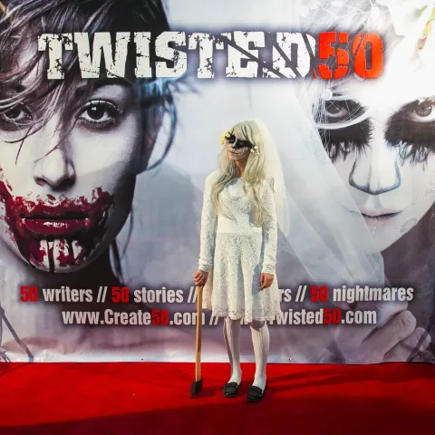 Two men standing in front of a poster for twisted 50.