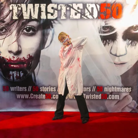 A man and woman posing in front of a poster for twisted 50.