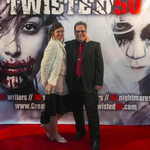 A woman and a girl standing next to a poster for twisted 50.