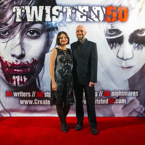 A man and woman posing on the red carpet for twisted 50.