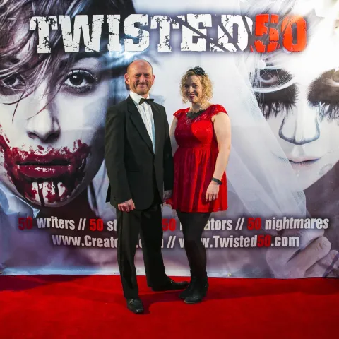 A woman and a girl standing next to a poster for twisted 50.