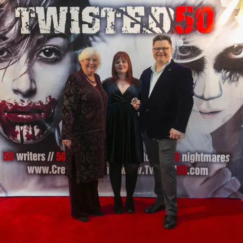 A woman and a girl standing next to a poster for twisted 50.