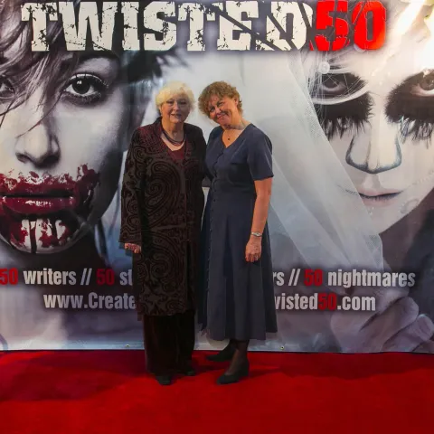 A man and woman posing on the red carpet for twisted 50.