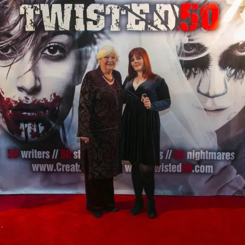 A man and woman posing on the red carpet for twisted 50.