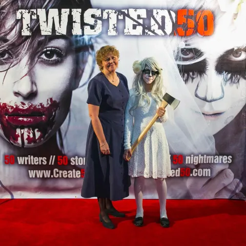 A woman and a girl standing next to a poster for twisted 50.