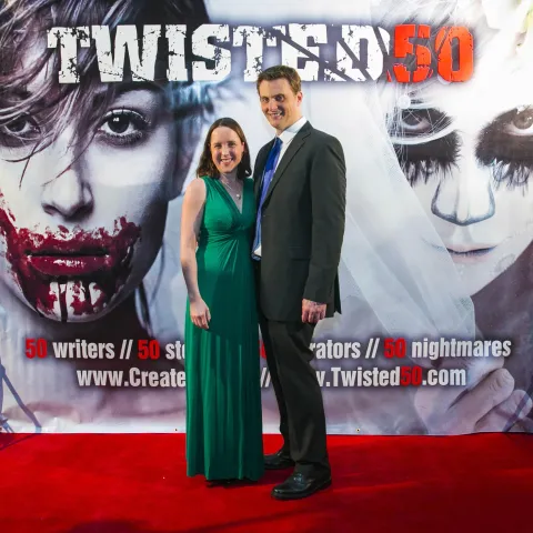 Two men standing in front of a poster for twisted 50.