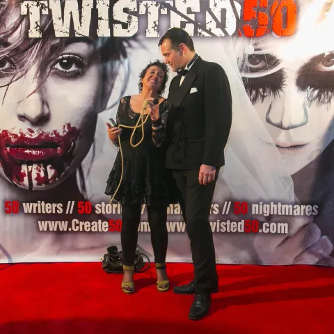 A man and woman posing on the red carpet for twisted 50.