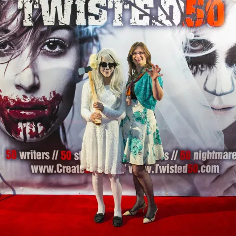Two men standing in front of a poster for twisted 50.