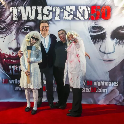 A woman and a girl standing next to a poster for twisted 50.