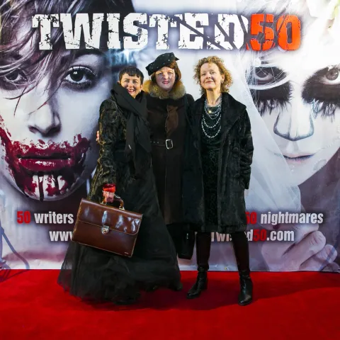 Three women posing for a photo on a red carpet.