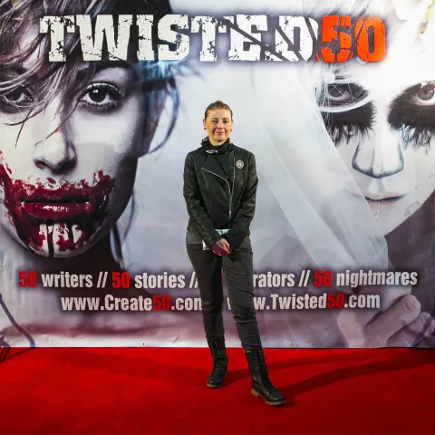 A woman and a girl standing next to a poster for twisted 50.