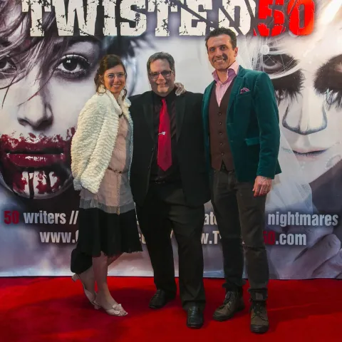 Two men standing in front of a poster for twisted 50.