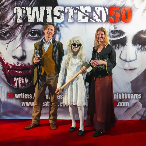 A man and woman posing in front of a poster for twisted 50.