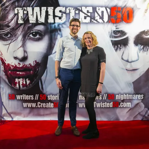 A woman and a girl standing next to a poster for twisted 50.