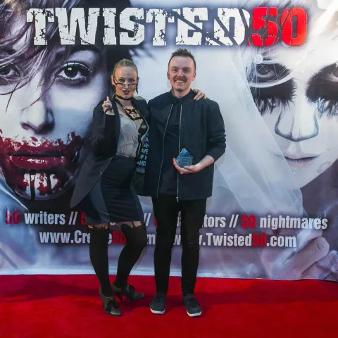 A woman and a girl standing next to a poster for twisted 50.