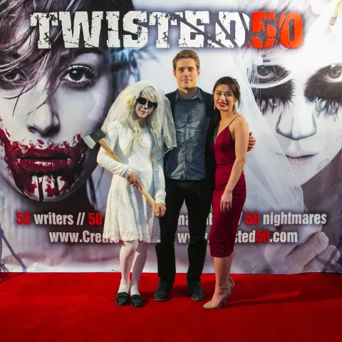 Three people posing on a red carpet for twisted 50.