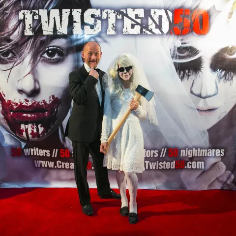 Two men standing in front of a poster for twisted 50.