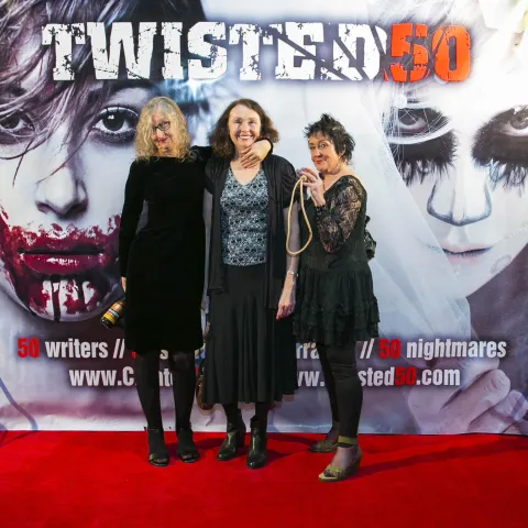Two men standing in front of a poster for twisted 50.