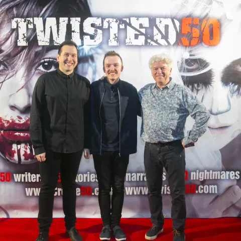 Two people posing for a picture on the red carpet at twisted 50.