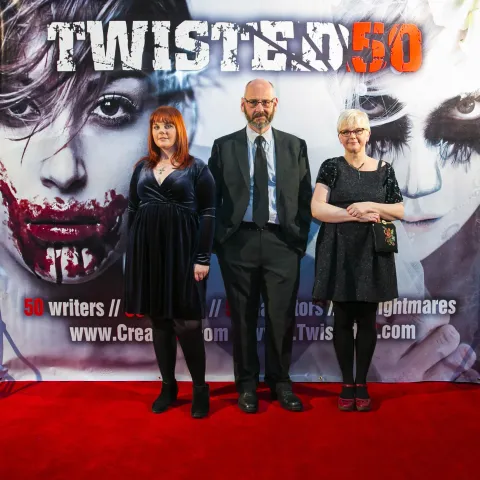 Three women posing for a photo on a red carpet.