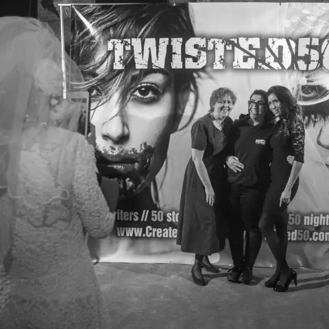 Two men standing in front of a poster for twisted 50.