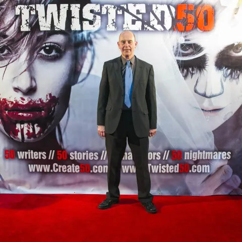Two men standing in front of a poster for twisted 50.