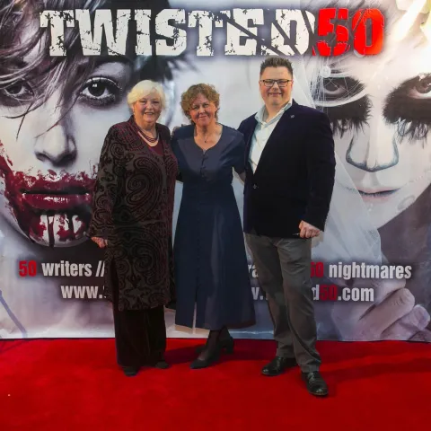 A group of people standing on a red carpet.