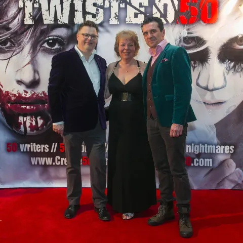 Three women posing for a photo on a red carpet.