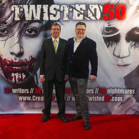 A man and woman posing in front of a poster for twisted 50.