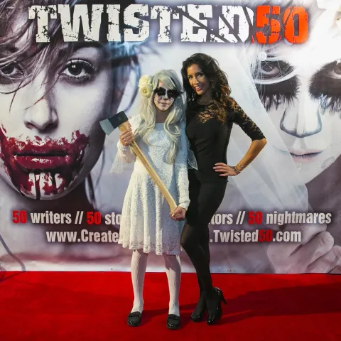 A man and woman posing in front of a poster for twisted 50.